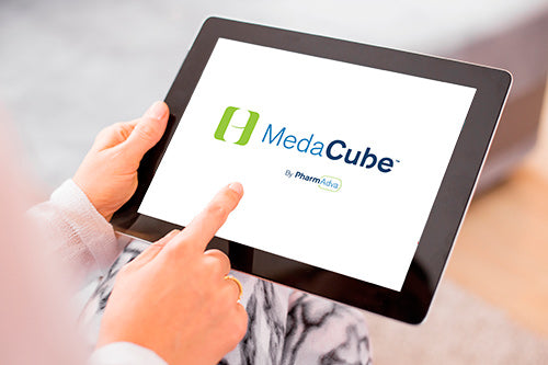 Hand holding a tablet and on the screen of the tablet displays the MedaCube logo.